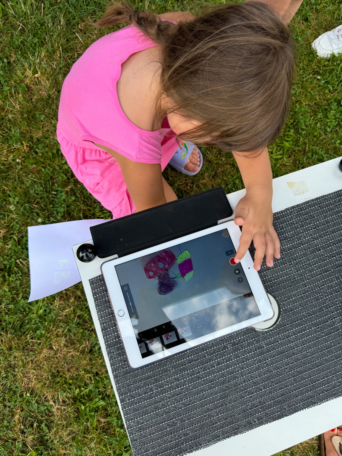 Auf dem Foto ist ein Mädchen von oben zu sehen, das gerade einen Legetrickfilm mit einem iPad und der Trickbox aufnimmt. 