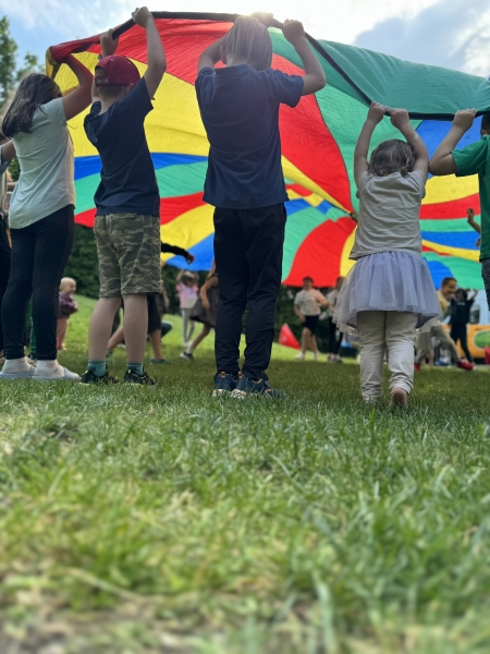 Kinder beim Spielen mit dem bunten Fallschirm