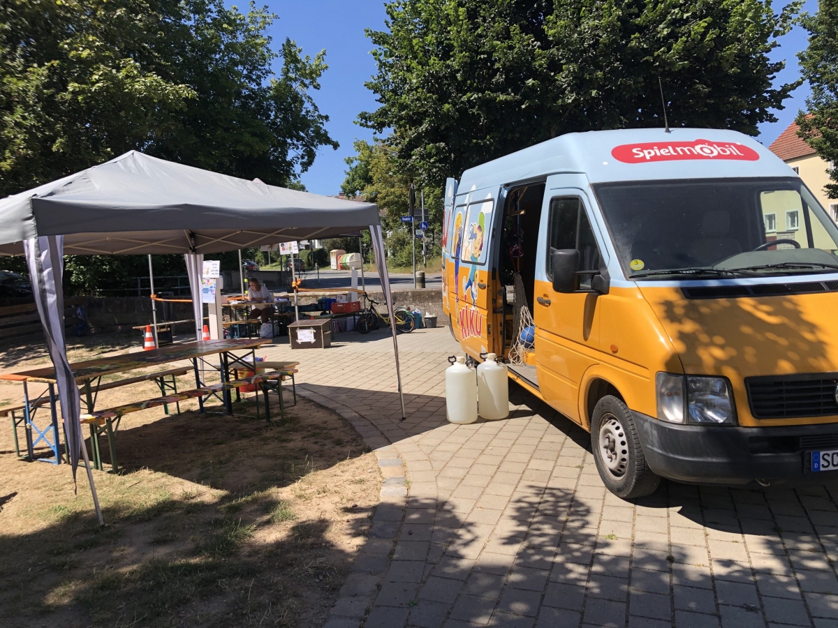 Das Spielmobil von vorne und ein Pavillon mit Bastelstation darunter.