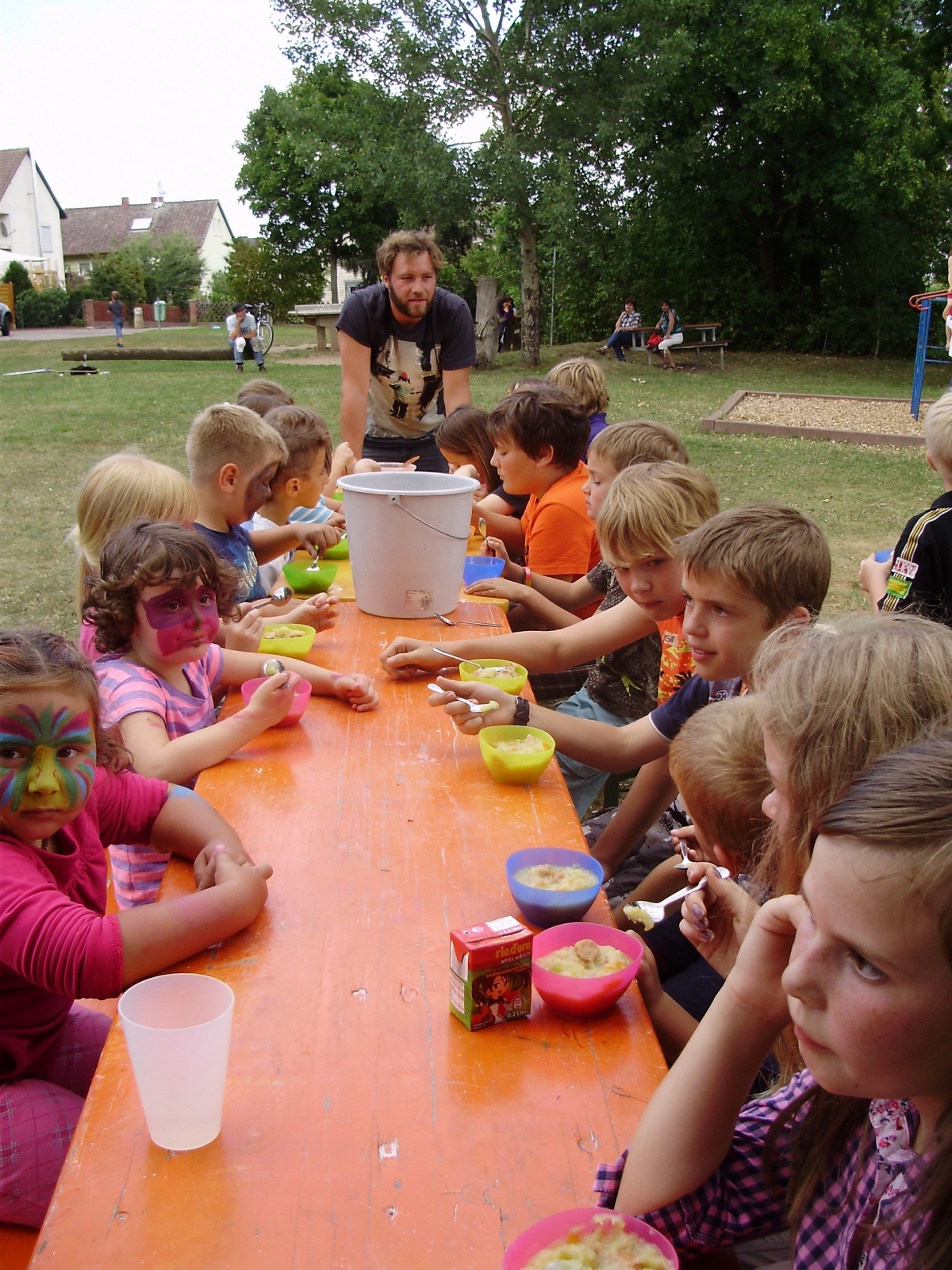Die Spielmobilkinder sitzen an einem Tisch und essen Kartoffelsuppe.