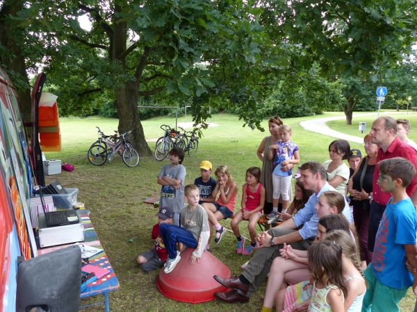 Die Kinder und der Oberbürgermeister schauen sich auf einem Laptop die entstandenen Filme der KiKU-Kinder an.
