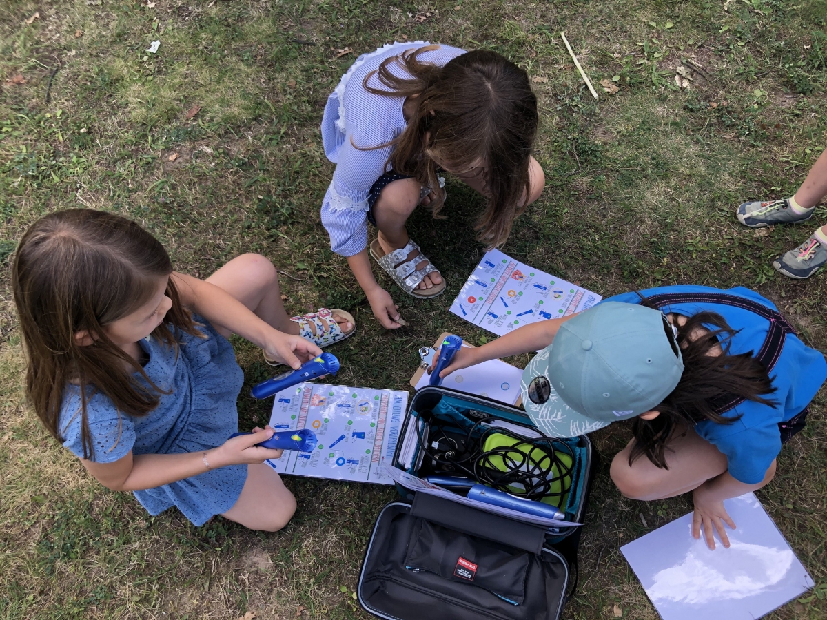 Drei Kinder sind von oben zu sehen, die gerade mit Tiptoi Stiften Symbole berühren.